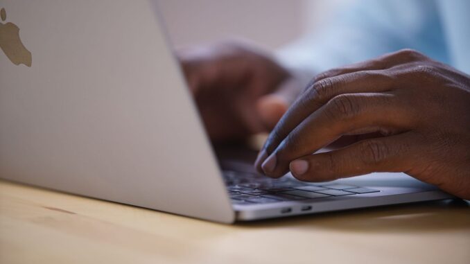 Hände tippen eine Suchanfrage auf einer Laptop-Tastatur