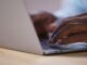 Hände tippen eine Suchanfrage auf einer Laptop-Tastatur